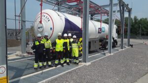Workers in hi-vis and hard hats standing in front of a tank.