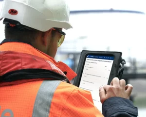 A terminal worker in high vis and hard hat looking at UAB-Online's software on a tablet