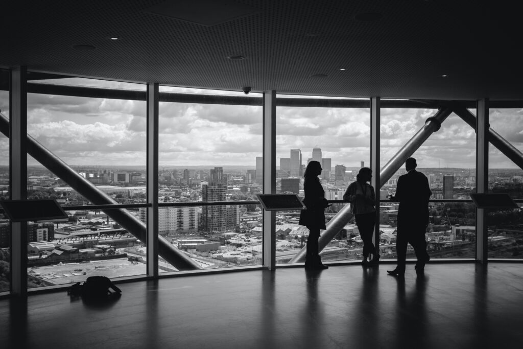 Three people in a room large window overlooking city.