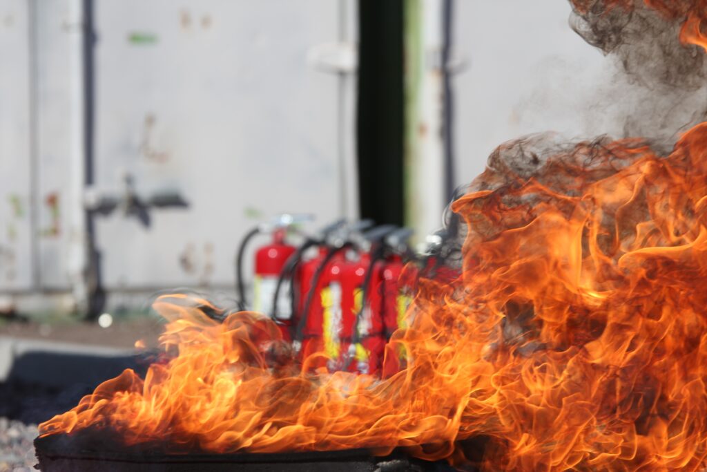 red fire extinguisher and fire in foreground