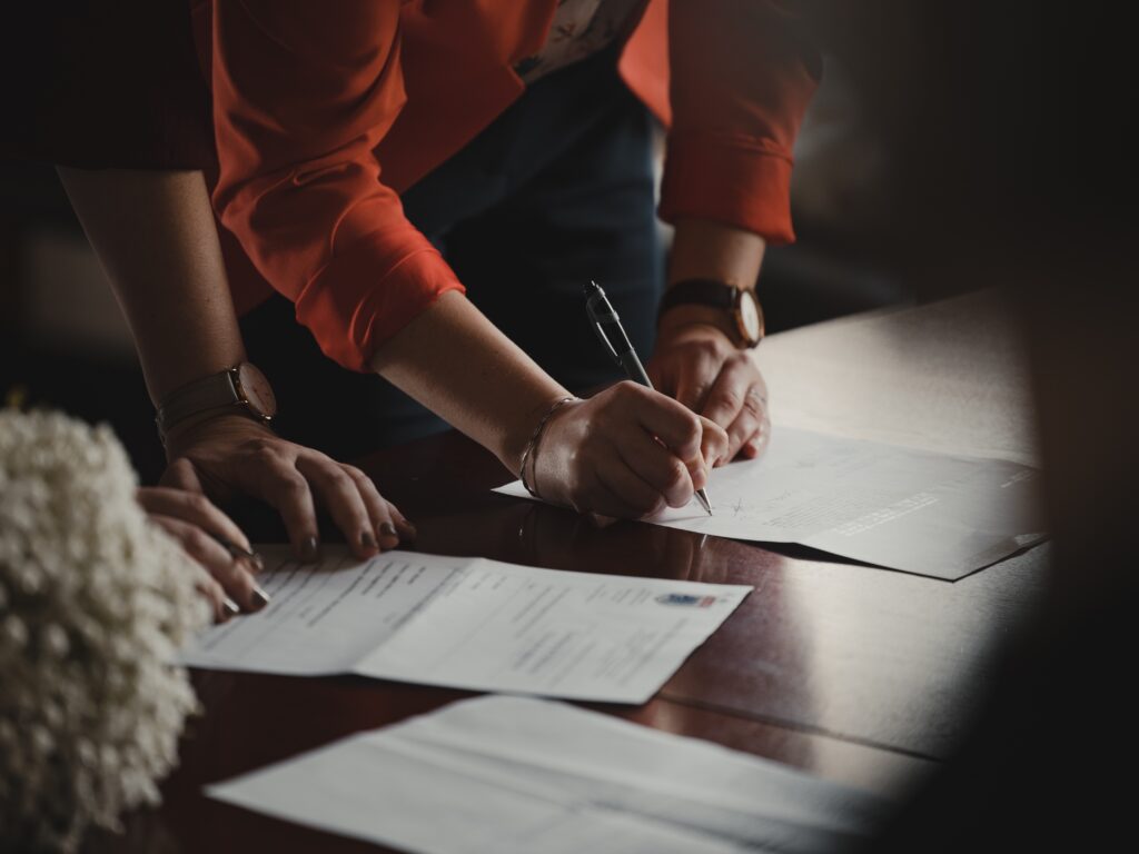 Two people leaning on desk signing papers