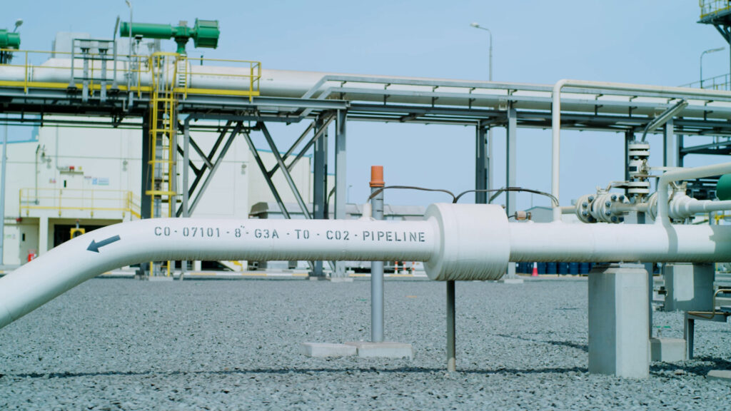 White pipeline in front of industrial site