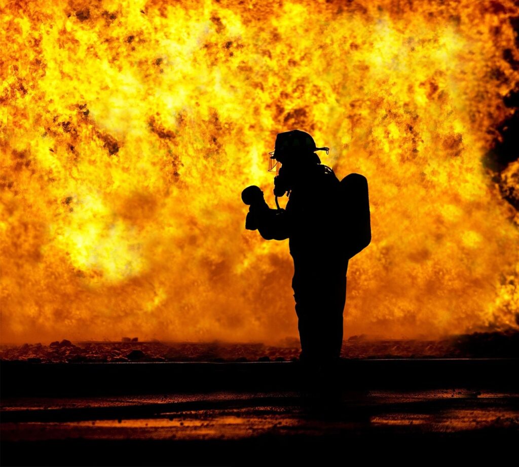 Silhoutte of firefighter set against orange flames