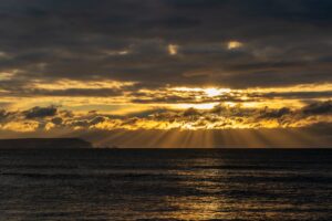 sun shining through clouds over water