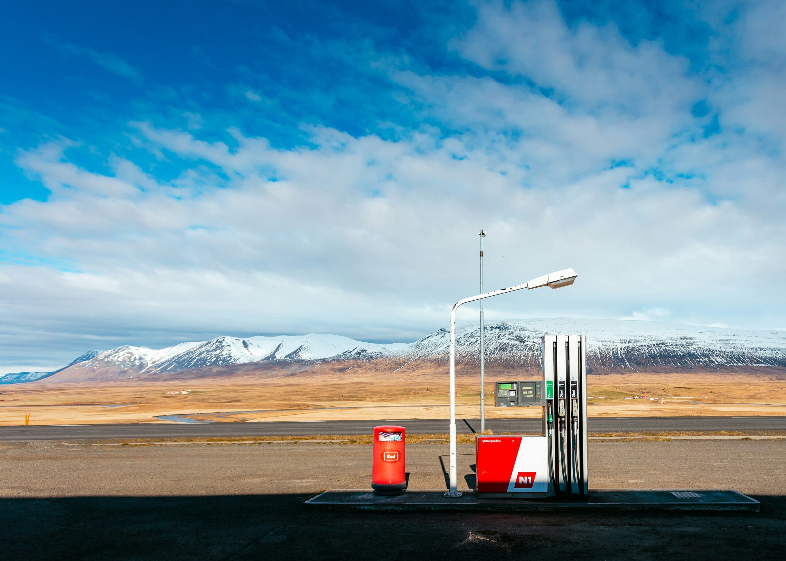 empty-gas-station-near empty road facing snow capped mountain at daytime