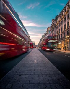 timelapse photography of red london double decker bus on road between buildings