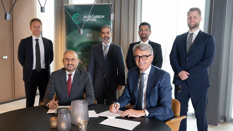 Six men standing looking at camera, signing papers.