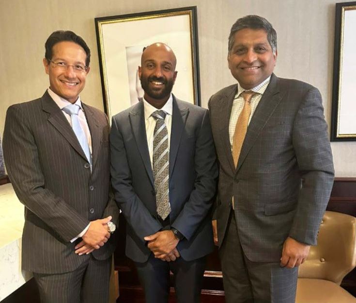 Three men standing and smiling.