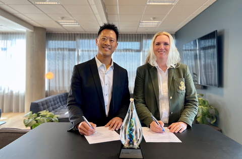 Man and woman smiling whilst signing papers with pen.