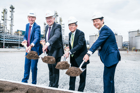 Four men in hard hats with shovels carrying mud.