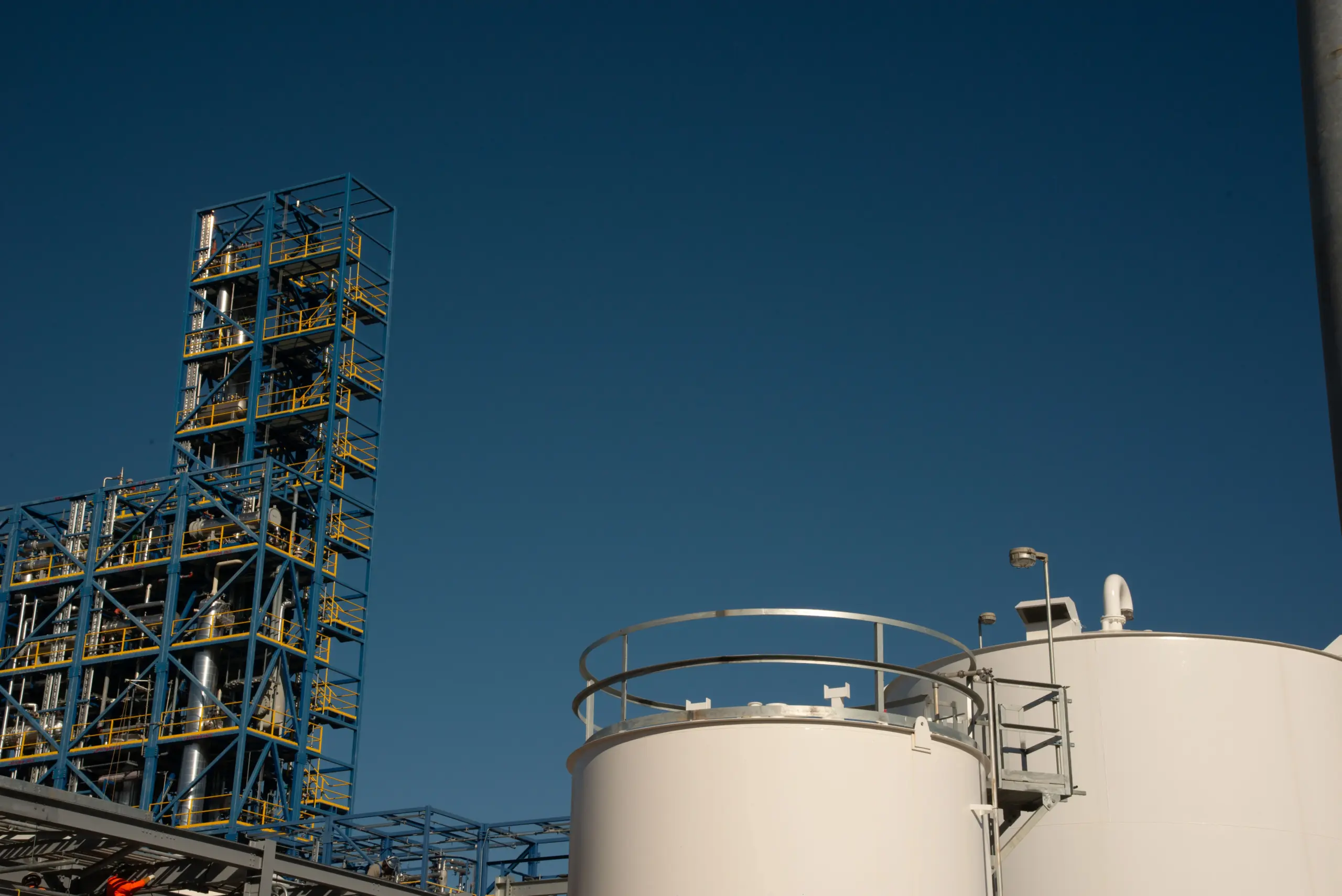 a large white tanks with a blue scaffolding