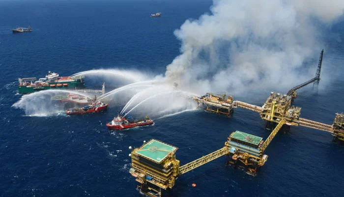 Fire boats spray water onto platform.