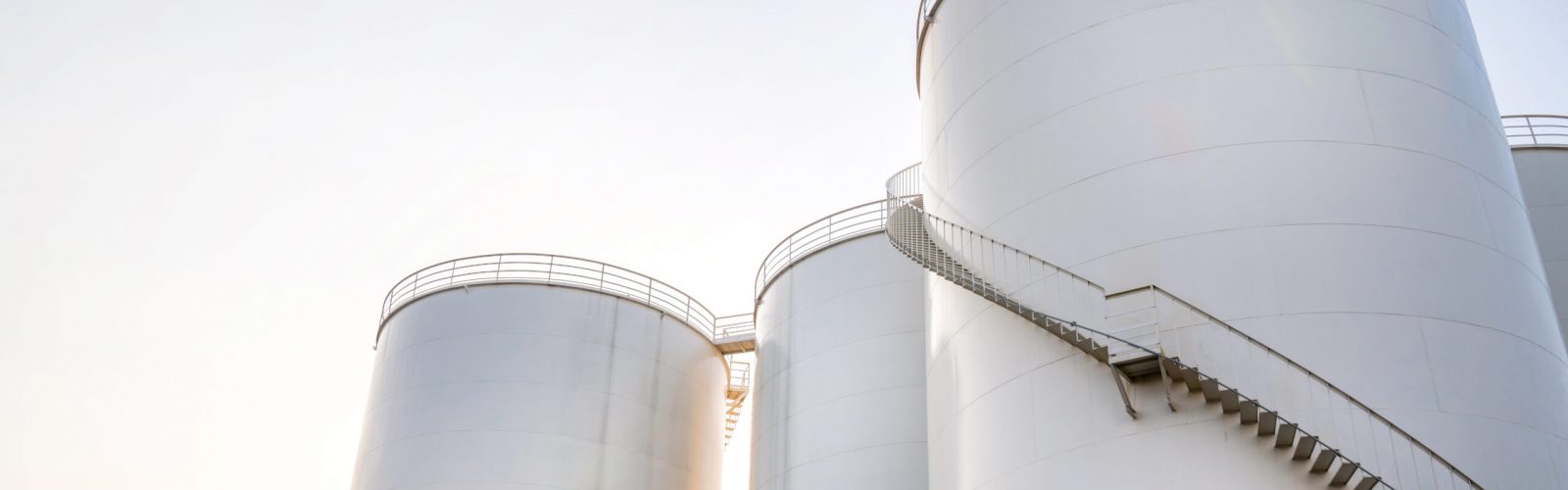 Curved stairway of base oil storage tank in the petroleum factory with blue sky. Industrial petroleum plant. Base oil for automotive engine oil and industrial oil application.