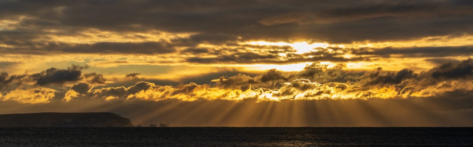 sun shining through clouds over water